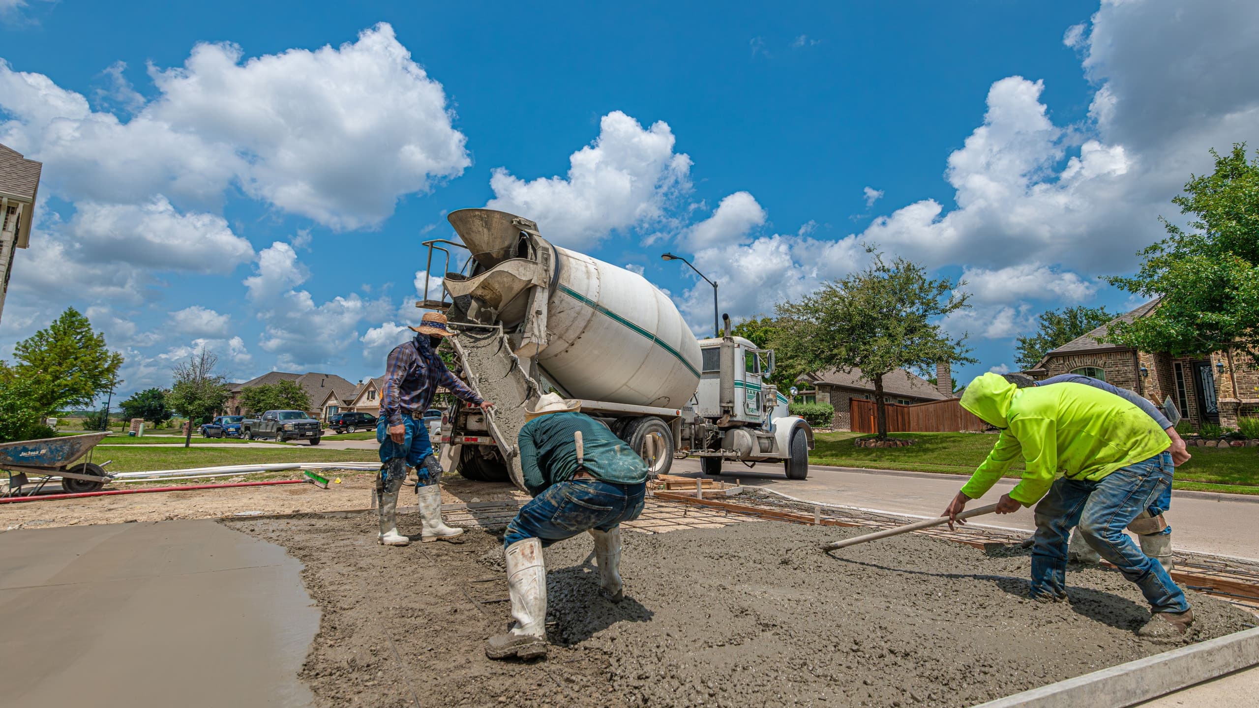 Concrete crew pouring and screeding a new residential driveway from a mixer truck